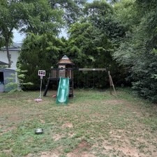 Before – backyard/playground: Backyard before landscaping in Raleigh, NC, with bare patchy lawn and play area