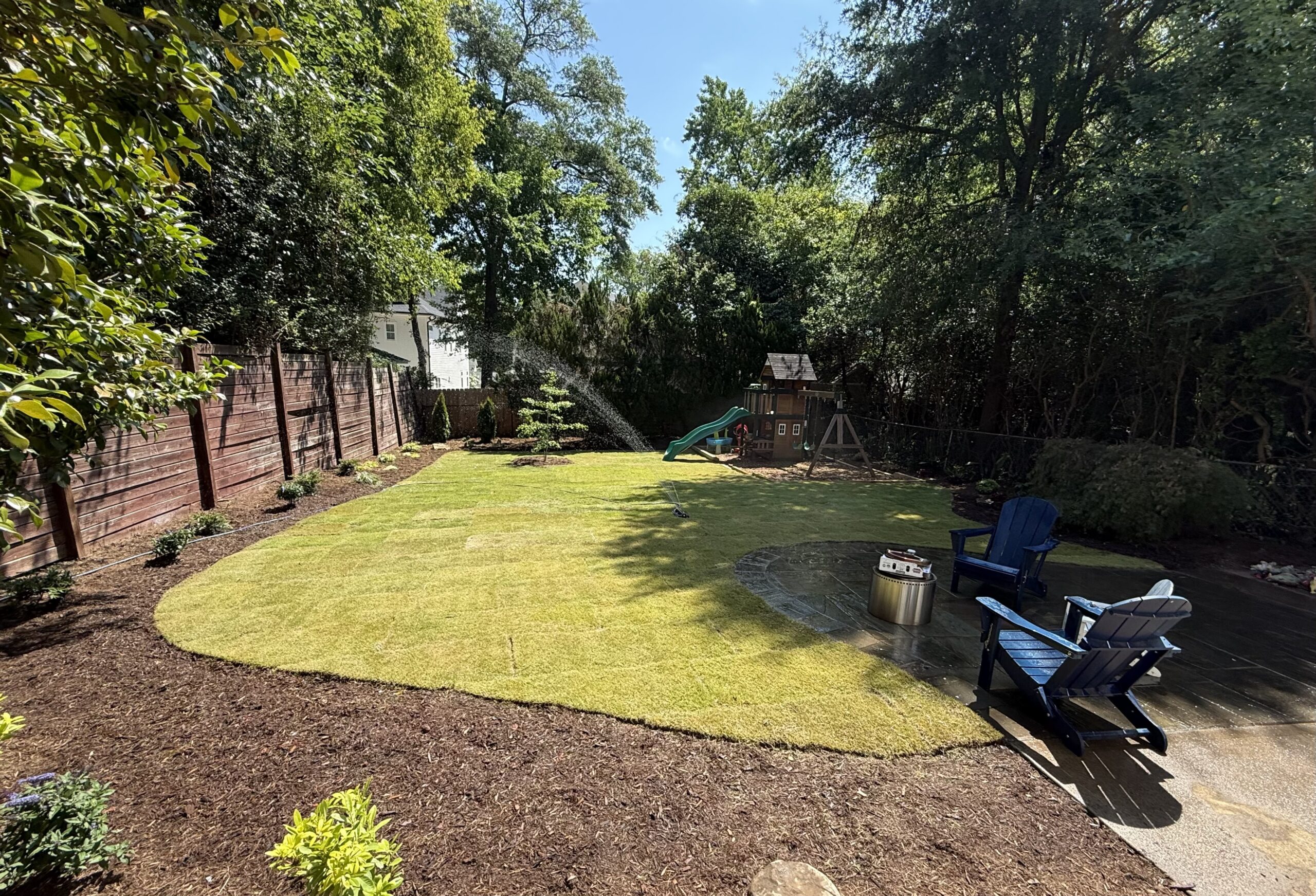 Raleigh Backyard Sod Installation New sod lawn and mulch beds in a Raleigh, NC backyard, with patio seating and play area in the background
