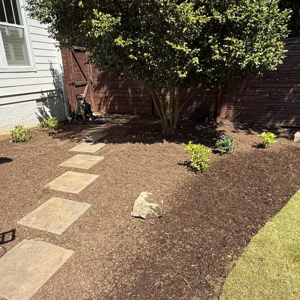 After – mulch bed with pavers: Mulch bed with stepping stone path and new plantings in a Raleigh, NC backyard